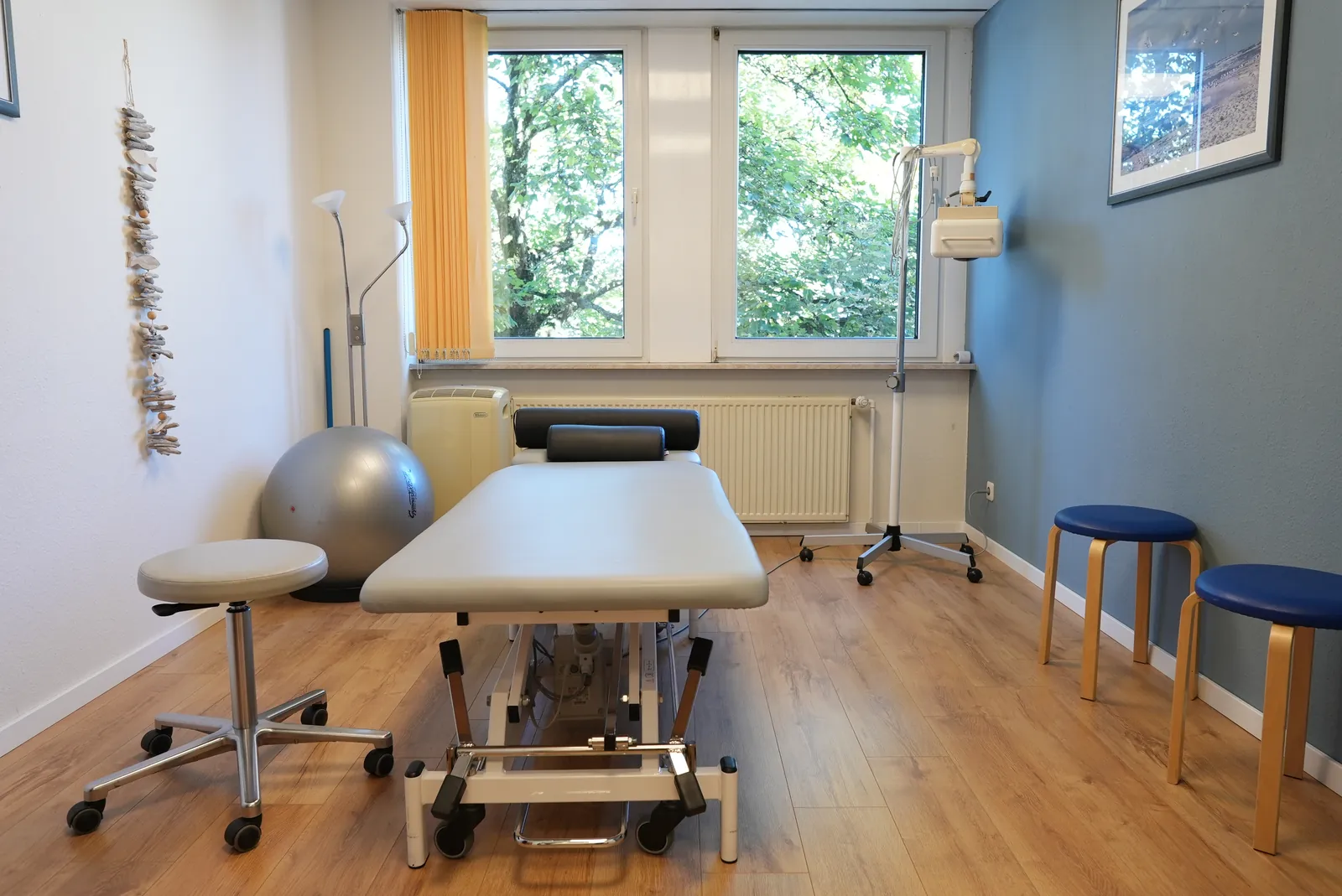Heller Behandlungsraum mit Therapieliege und Pezziball